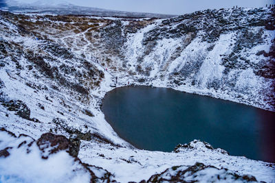 Scenic view of snow covered mountains by lake against sky