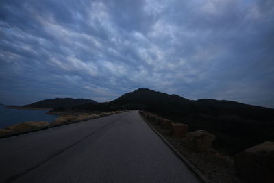 Scenic view of road by mountains against sky