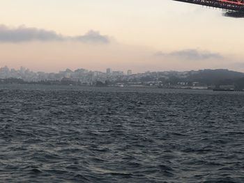 Scenic view of sea by city against sky during sunset