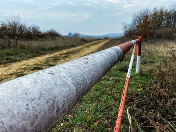 Pipe on field by road against sky