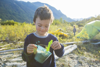 Young boy smiling while eating breakfast at campsite