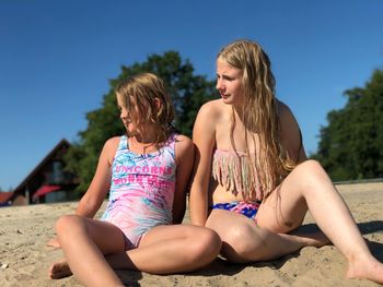 Sisters sitting on sandy beach