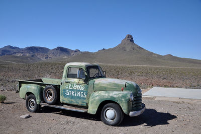 Vintage car on desert against clear blue sky