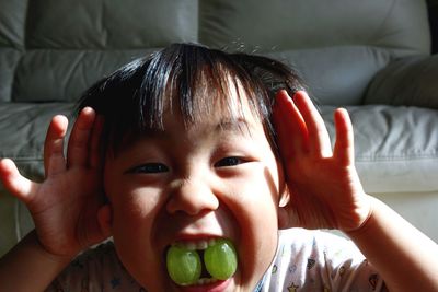 Portrait of cute baby boy biting grapes at home