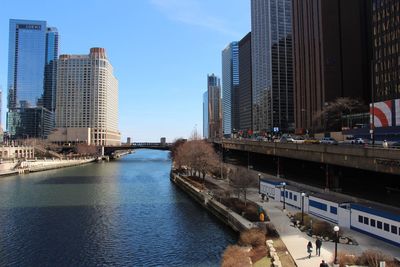 Bridge over river by buildings against sky in city