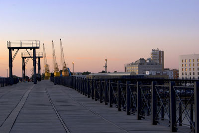 Bridge by buildings against sky during sunset