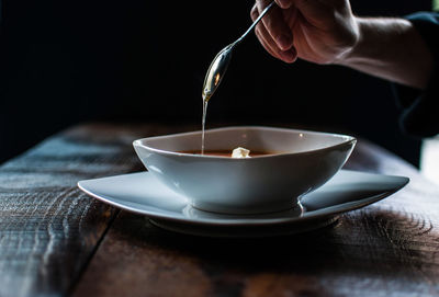 Cropped hand of man having soup on table at restaurant