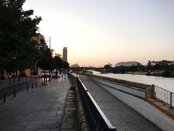 People walking on bridge in city against clear sky
