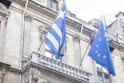 Low angle view of flags on buildings against blue sky