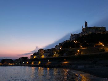 Illuminated buildings against sky at sunset