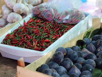 Chili peppers and figs in containers at market for sale