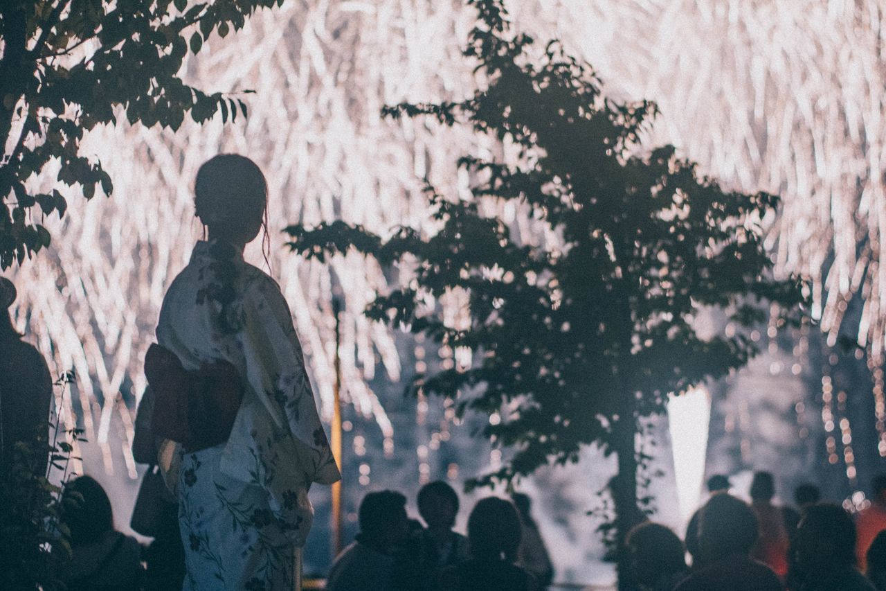 REAR VIEW OF PEOPLE WALKING BY TREE