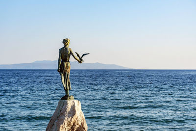 Statue by sea against clear sky