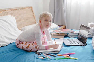 Portrait of cute girl studying on bed