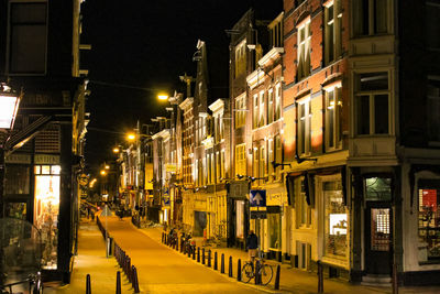 Illuminated street amidst buildings at night