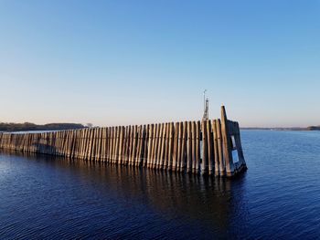 Pier over sea against clear blue sky