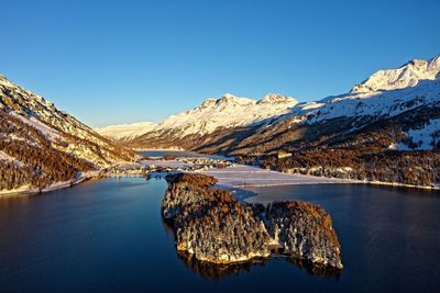 Scenic view of lake and snowcapped mountains against clear blue sky