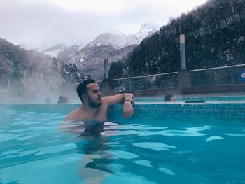 Man looking away while relaxing in hot spring pool