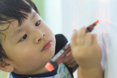 Close-up portrait of cute boy holding camera