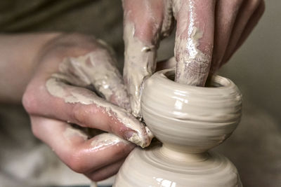 A man with his hands dub wall jug, which he sculpts out of clay on a circle. create clay vessel. 