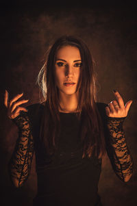 Portrait of young woman gesturing while standing against abstract background