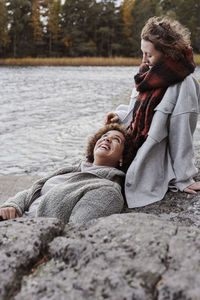 Female couple relaxing on rocks by lake