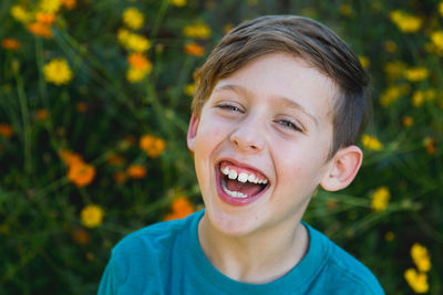 Close-up portrait of laughing boy against flowers