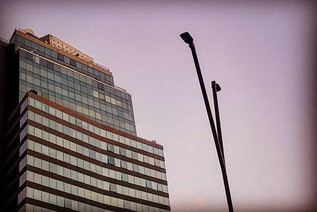 low angle view, architecture, building exterior, built structure, clear sky, street light, tall - high, building, city, sky, tower, skyscraper, outdoors, no people, pole, tall, office building, modern, day, copy space