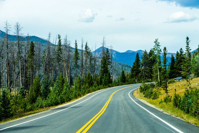 Road by trees against mountains