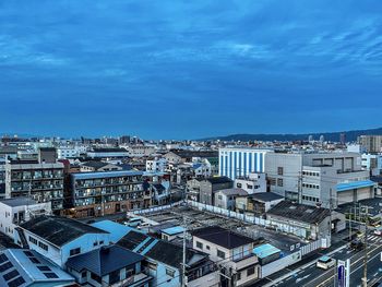 High angle view of city buildings against blue sky