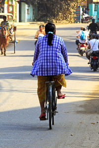 Rear view of people riding bicycle on road