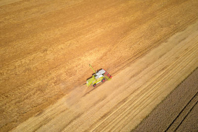 Aerial view of working harvesting combine in wheat field, harvest season