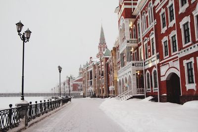 Street amidst buildings against sky in city during winter