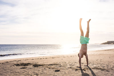 Full length of woman walking on beach against sky
