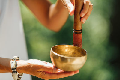 Hands holding tibetan singing bowl outdoors, playing calming sounds