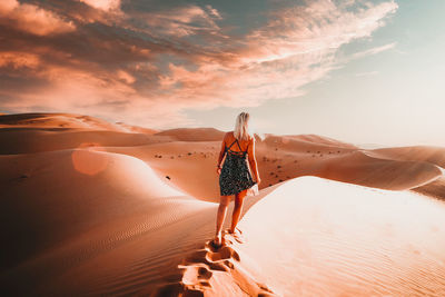 Rear view of woman on sand dune against sky