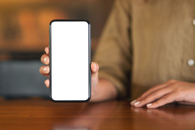 Midsection of woman using smart phone in cafe