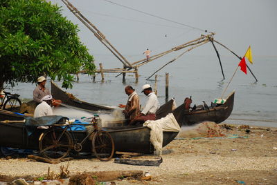 People fishing at beach against sky