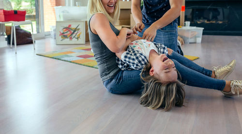 Rear view of women relaxing on floor at home