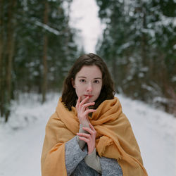 Woman stands in a winter forest with a yellow scarf