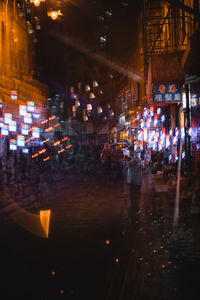 People walking on illuminated street at night