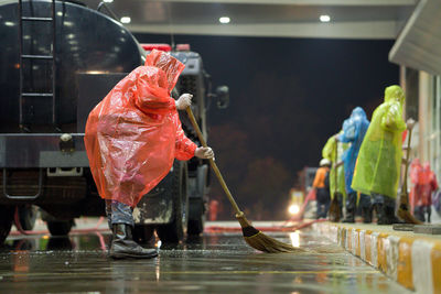 Person sweeping on wet road at night