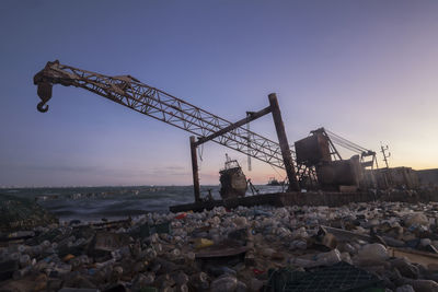 Beach full of plastic bottles and other waste with shipwreck in the background at sunrise