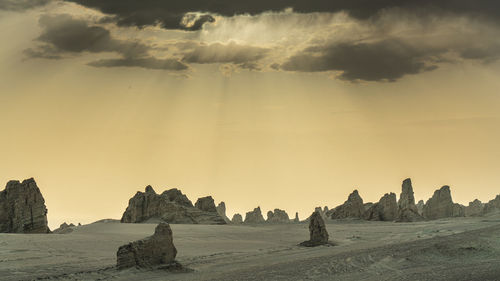 Panoramic view of rocks on land against sky during sunset