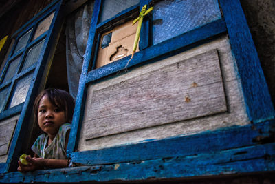 Low angle view of girl looking through window