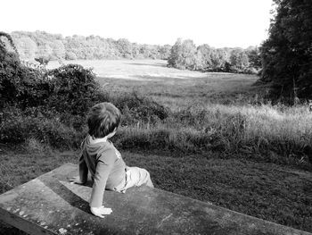 Rear view of boy sitting on field