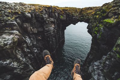 Low section of woman on cliff by sea