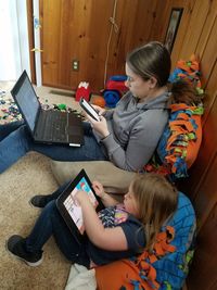 Rear view of siblings sitting on laptop at home