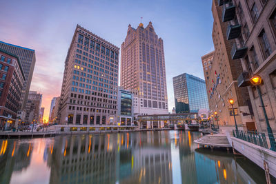 Reflection of illuminated buildings in city at dusk