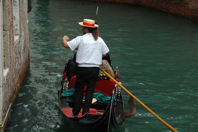 Rear view of man standing on boat in canal